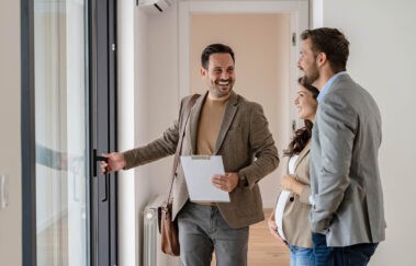 real estate agent opens door for clients