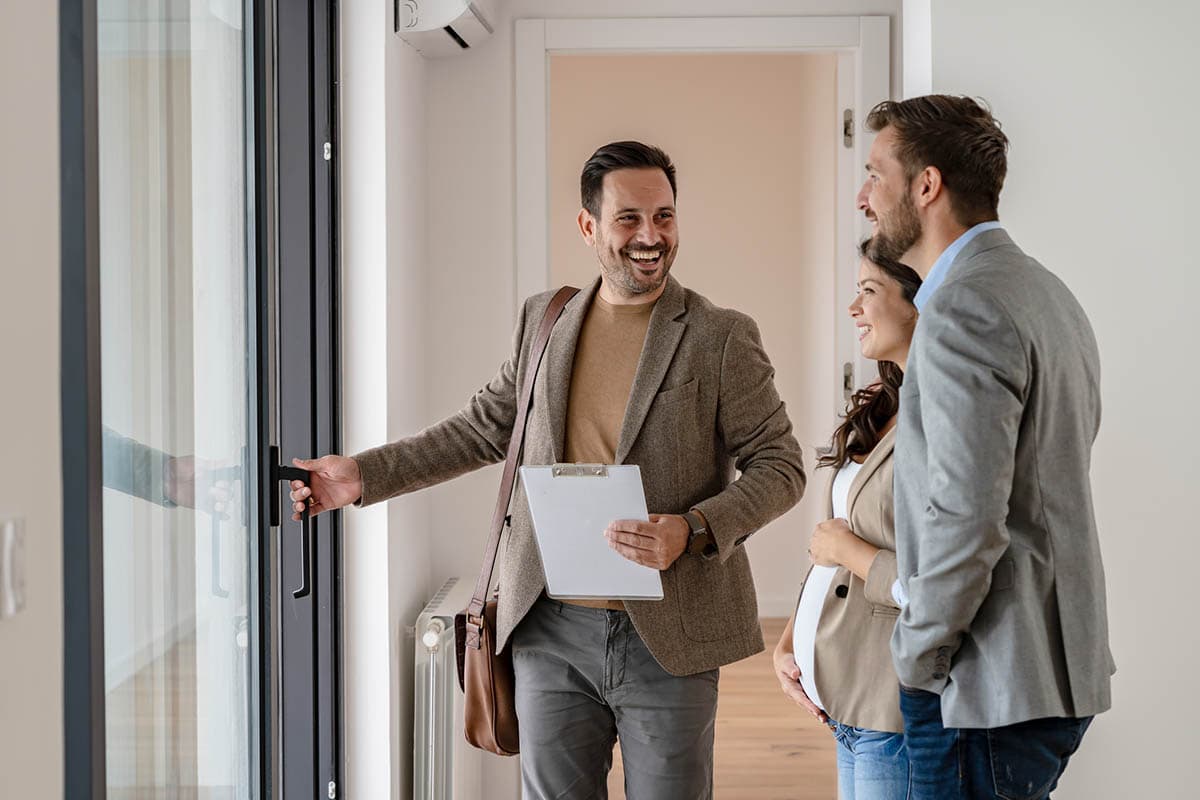 real estate agent opens door for clients